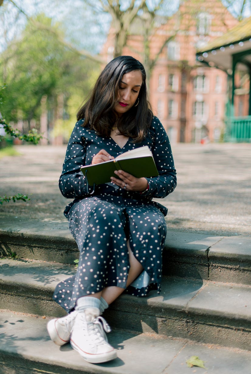 Female adult looking down at sketchbook pretending to draw, whilst sitting on steps outside Female adult looking down at sketchbook pretending to draw, whilst sitting on steps outside