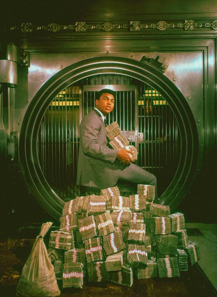 This may contain: a man in a suit and tie sitting on top of stacks of boxes next to a machine This may contain: a man in a suit and tie sitting on top of stacks of boxes next to a machine