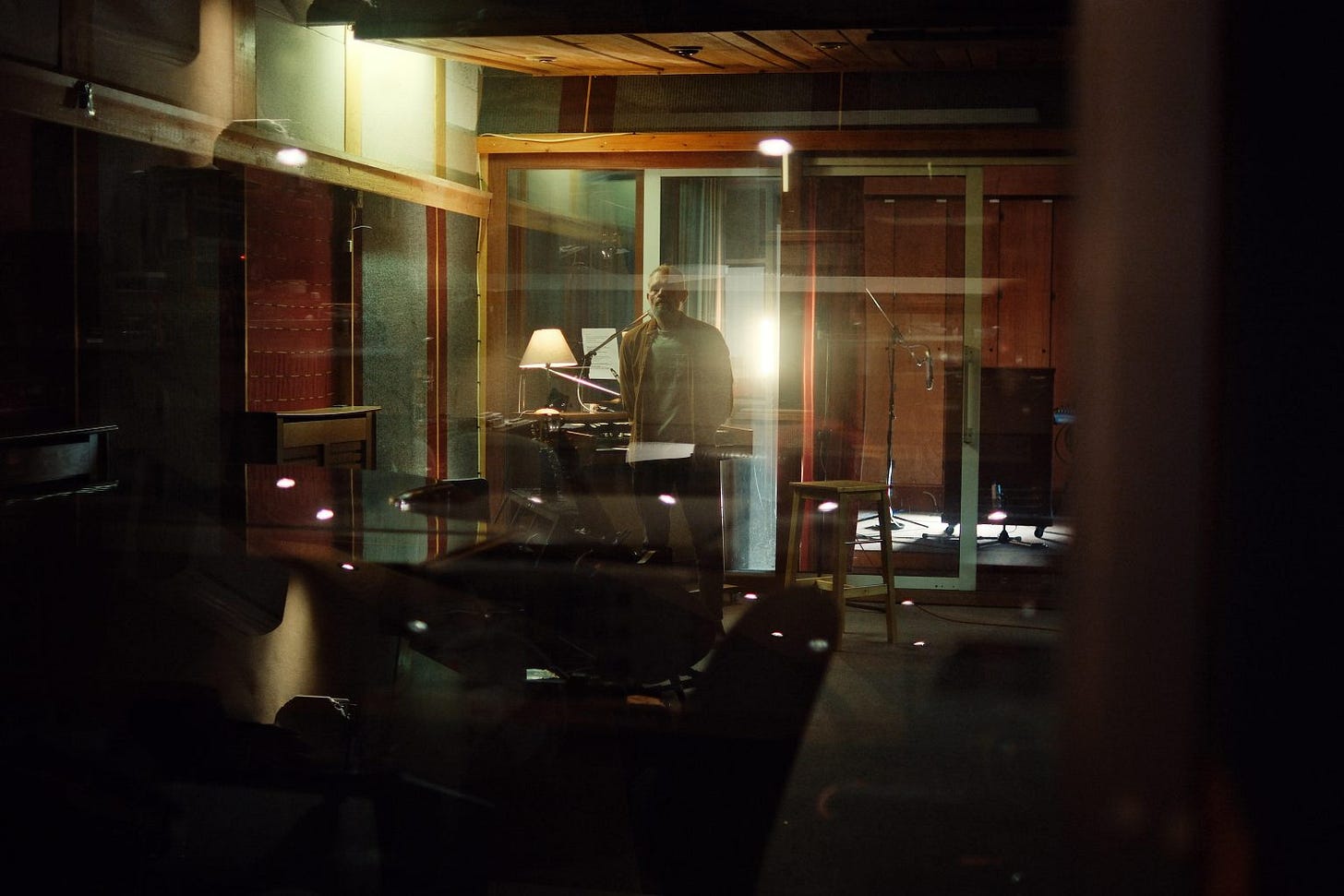 A photo of Matt Hegarty of Matthew and the Atlas. He stands at the back of a dimly lit music studio.