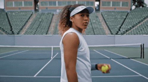 a woman is holding a tennis ball on a court