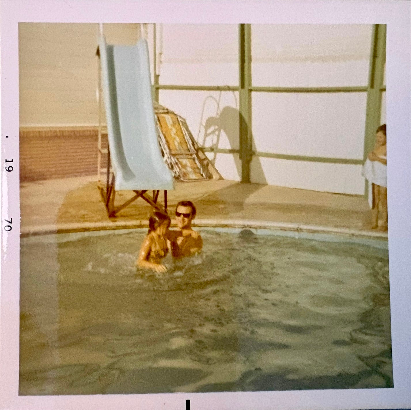 girl and father in swimming pool with a slide