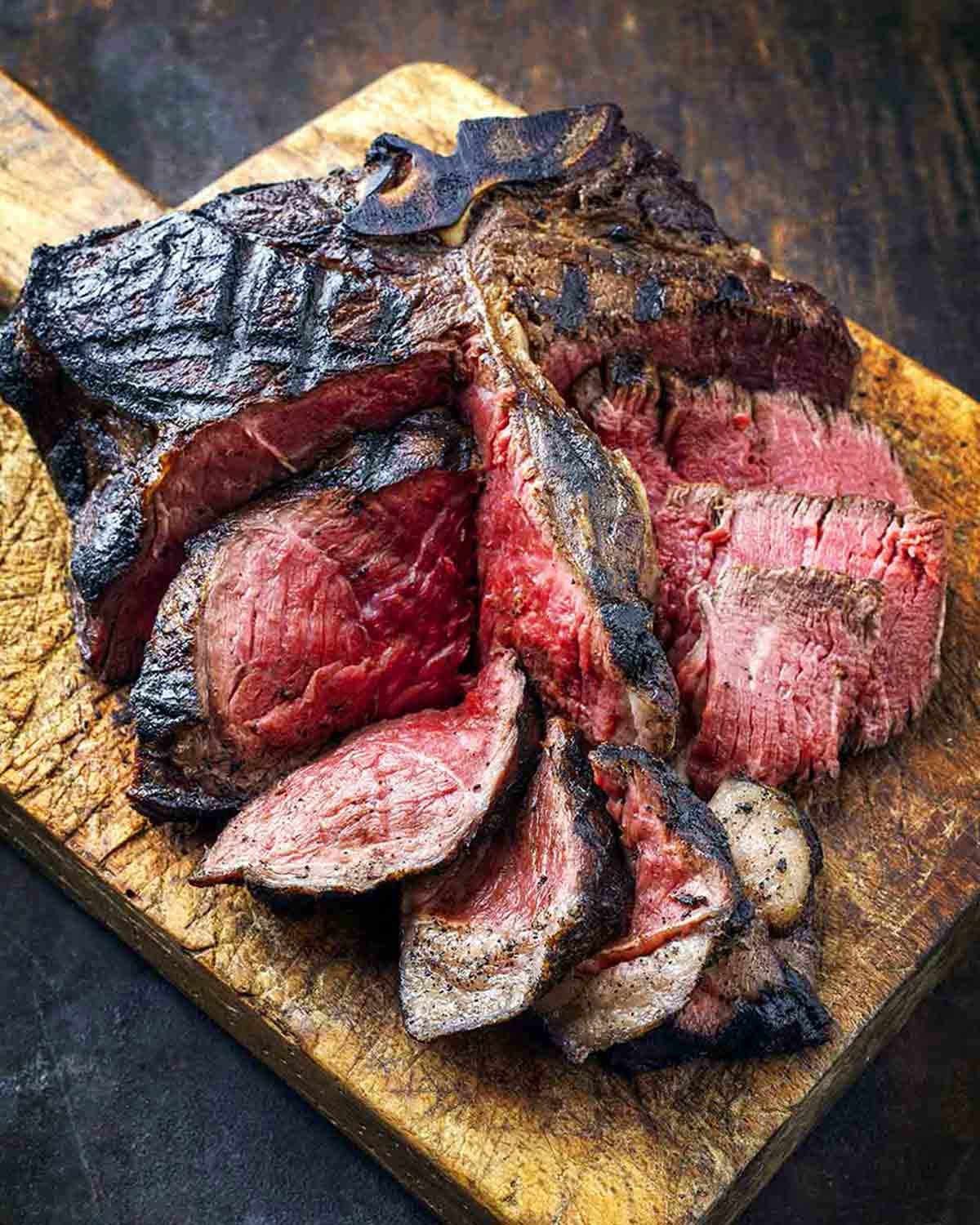 A thick, grilled porterhouse steak with perfect grill marks, sliced open to show a juicy, medium-rare center.