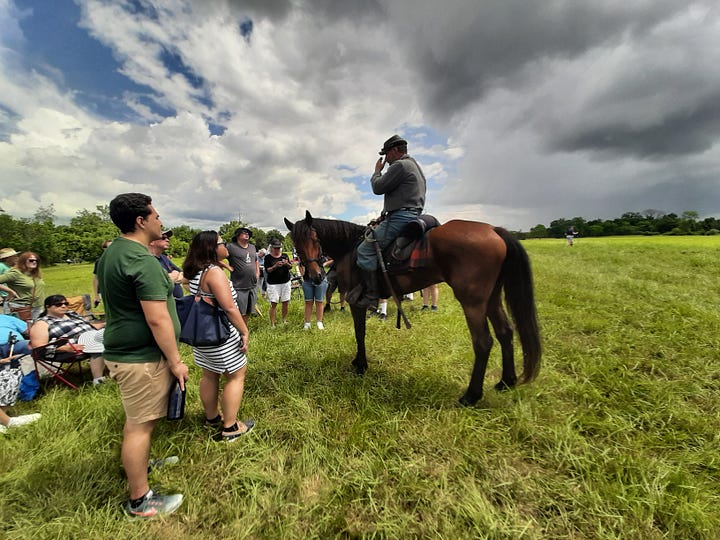 Period dressed riders on horses stand close to the cord, answering questions.