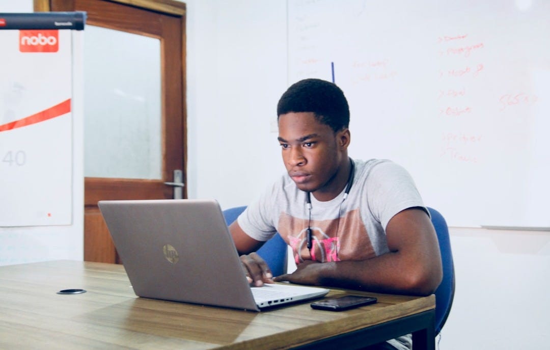 man in grey shirt using grey laptop computer man in grey shirt using grey laptop computer