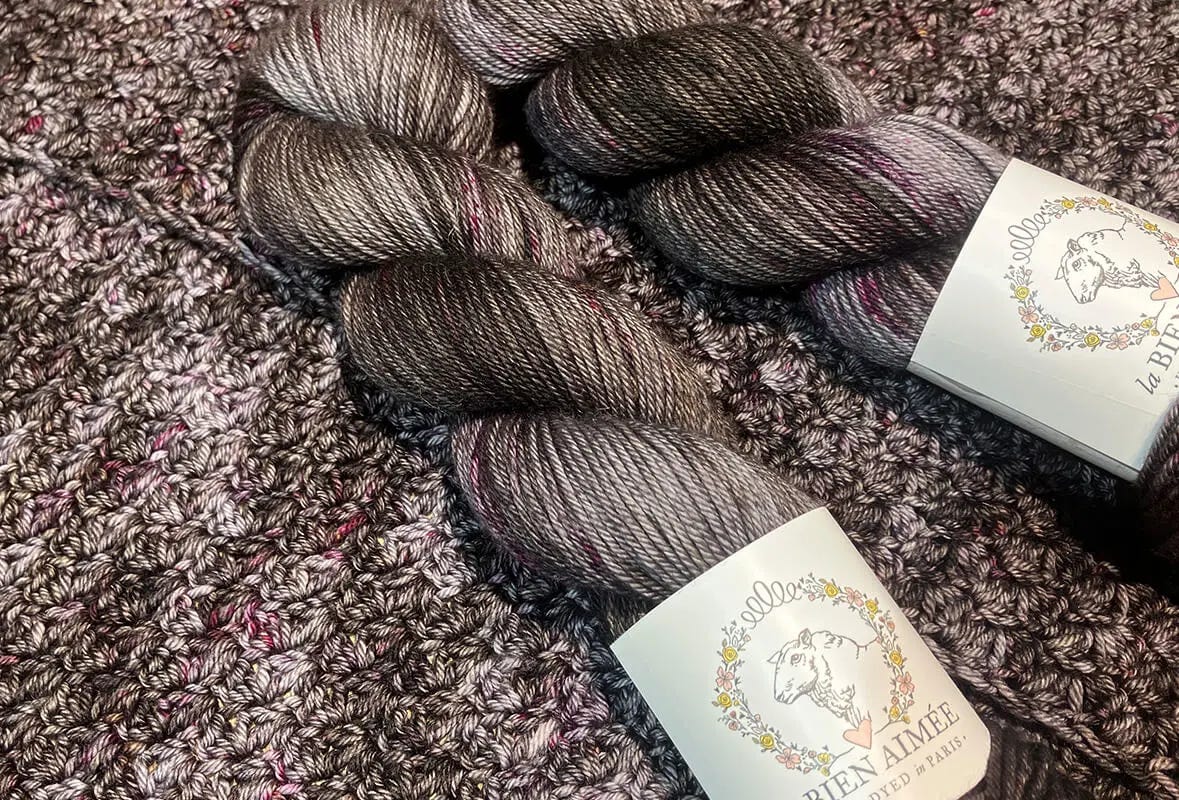 two grey yarn skeins on crochet fabric
