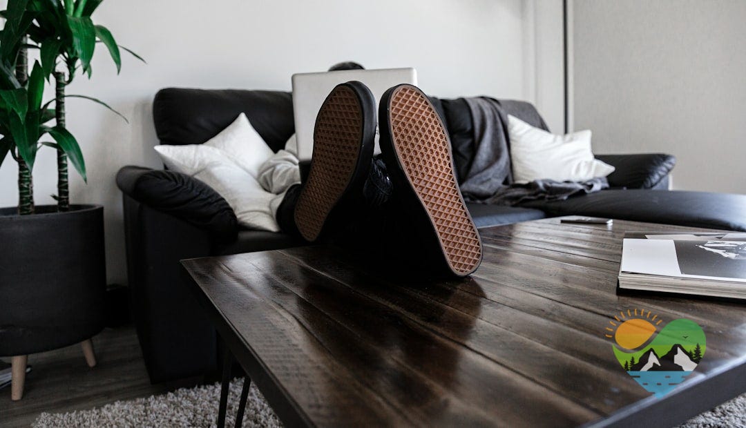 person sitting on sofa resting its feet on top of coffee table while using laptop