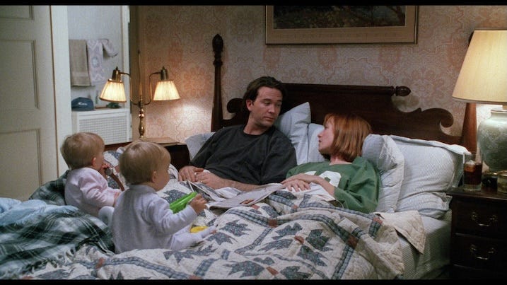 Thad Beaumont lies in bed with his wife, played by Amy Madigan, as their twin toddlers sit between them. The room is softly lit, warm, and intimate — a moment of calm before the storm.