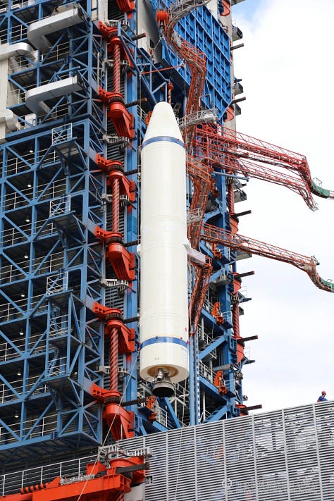 The Long March 3B/E's payload adapter and second-stage being prepared for flight, as well as a first-stage booster being lifted during assembly for launch.