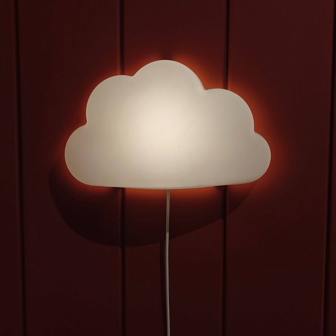 A cloud shaped night light hanging on a red wall A cloud shaped night light hanging on a red wall