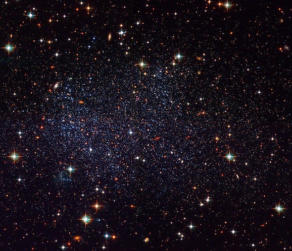 An image taken by the Hubble Space Telescope showing the Sagittarius Dwarf Irregular Galaxy (SagDIG). The image reveals thousands of individual stars within SagDIG, appearing as a dense field of stars with varying brightness and colors, ranging from blue to red. The background is dark, highlighting the multitude of stars. The text above the image notes that Hubble's sharp vision has provided a detailed view of this relatively nearby galaxy. An image taken by the Hubble Space Telescope showing the Sagittarius Dwarf Irregular Galaxy (SagDIG). The image reveals thousands of individual stars within SagDIG, appearing as a dense field of stars with varying brightness and colors, ranging from blue to red. The background is dark, highlighting the multitude of stars. The text above the image notes that Hubble's sharp vision has provided a detailed view of this relatively nearby galaxy.