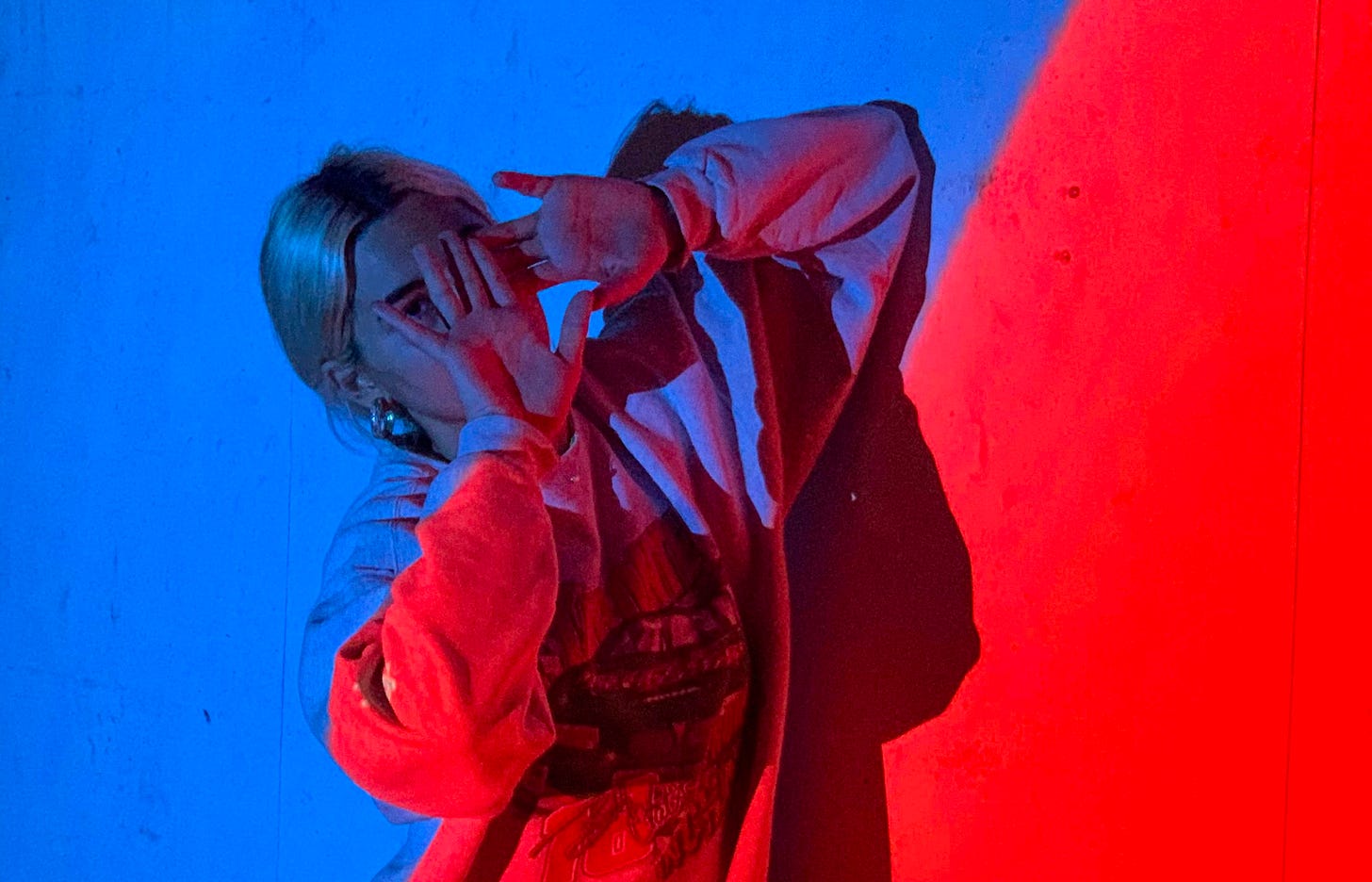 woman in red jacket covering her face with her hands