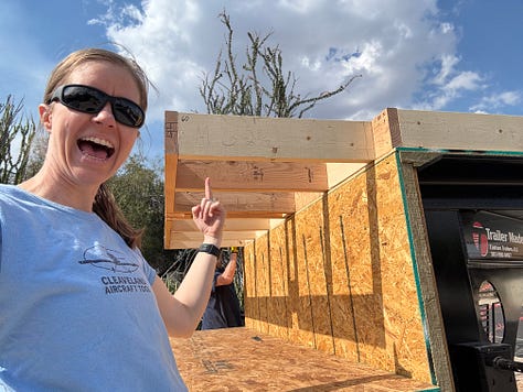 A picture of a yellow spiral notepad with several rows of instructions next to a color-coded framing diagram; Kendra with an open-mouth smile, pointing up toward a cantilevered section of floor framing; A view of the floor framing diagramed in image 1 built out and on the gooseneck portion of the trailer