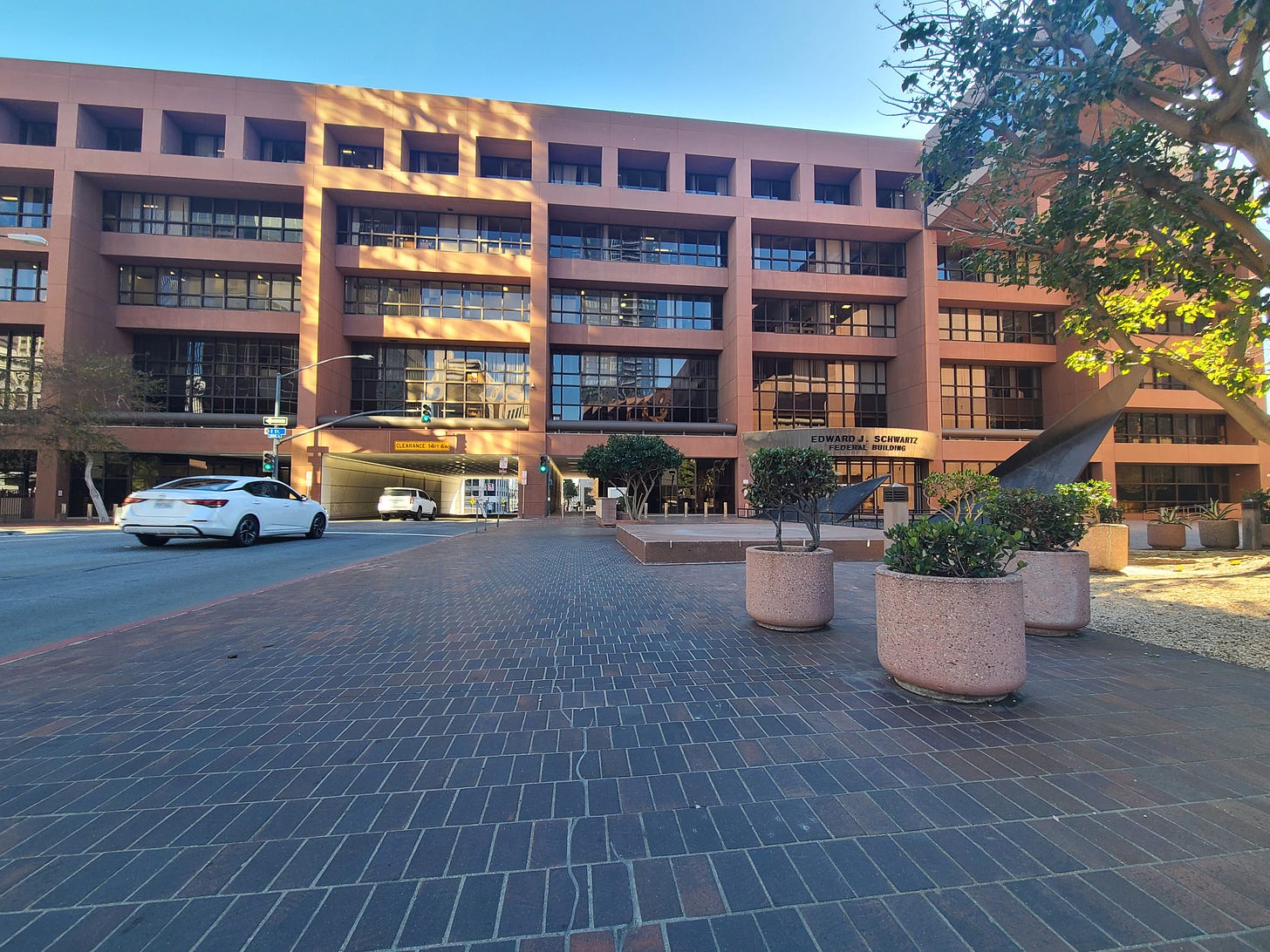 A brown building with a tunnel for cars to pass through and a brick sidewalk