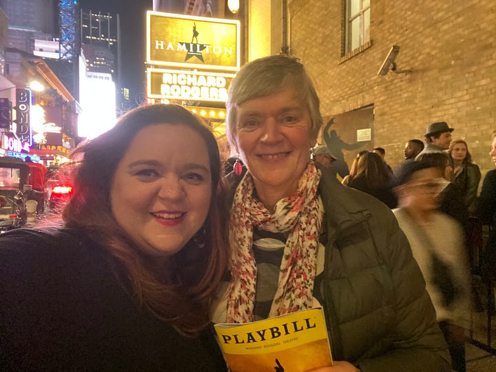 two women smiling outside a theatre and a woman eating a hotdog