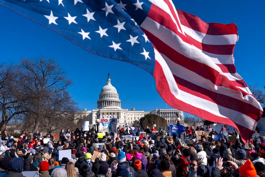 An American flag flies upside-down above a group of protesters gathered near the U.S. Capitol Building.