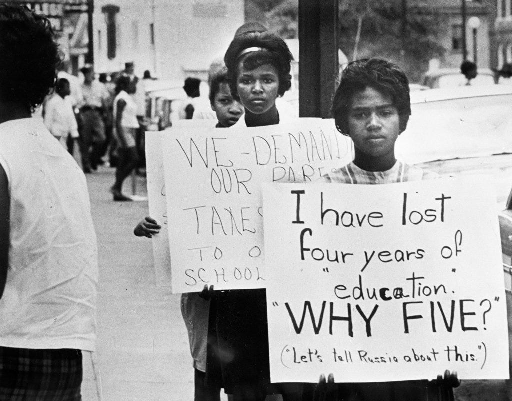 Young women with homemade signs protest school closings in Farmville