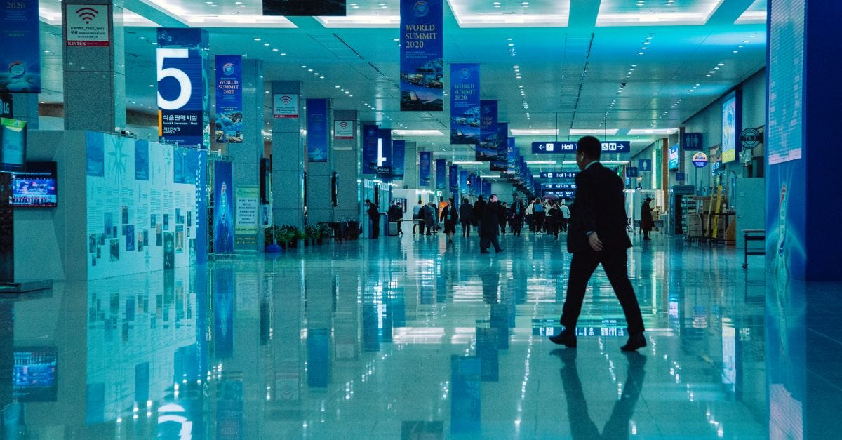 Photo: wal_ 172619 / Pexels An indoor view of a busy conference hall during World Summit 2020 with directional signs and reflections.