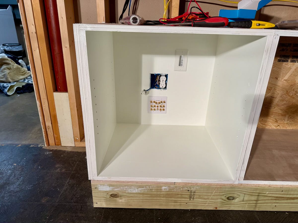 One box of a built-in cabinet showing various electrical and wiring receptacles mounted inside.