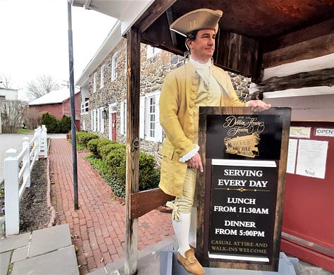 Outside of the stone Dobbin House restaurant; a welcome sign for the Springhouse Tavern and a closeup of candle-style lighting/ A sign for the Slave Hideout Museum, and a display of 3 slaves hiding in a crawl space. The owner of the restaurant stands in front of a huge stone fireplace in a room set up as a colonial kitchen.