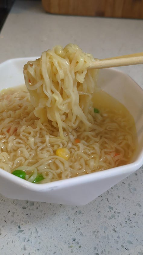 Classic chicken instant ramen cup being opened, cooked, and held up by chopsticks.