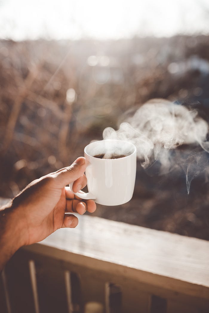 A steaming cup of coffee held aloft. A steaming cup of coffee held aloft.