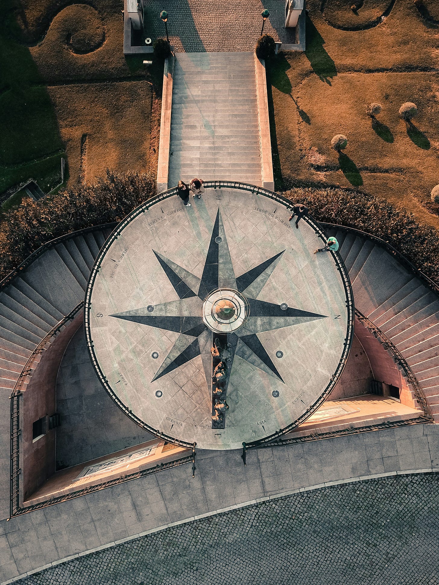 Terrace with a pattern of compass at the center. People linger around it, sitting or leaning on the side rail.