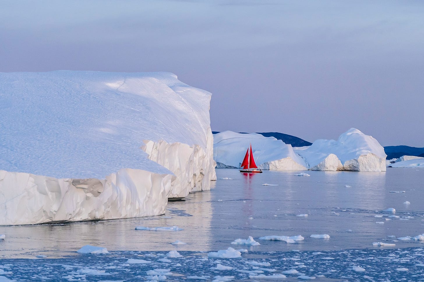 Una barca rossa naviga tra i ghiacci di Disko Bay, in Groenlandia Una barca rossa naviga tra i ghiacci di Disko Bay, in Groenlandia