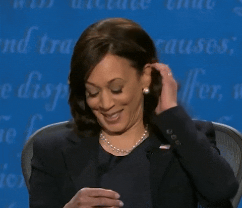 Kamala Harris smirks and brushes her hair back during the 2020 vice presidential debate, reacting with visible amusement.