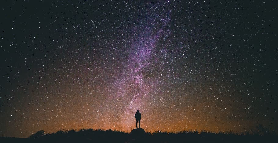 silhouette of person looking up at star-rich night sky