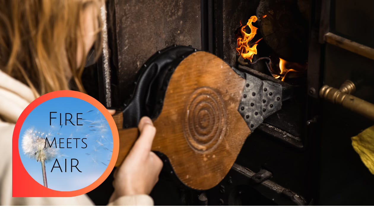 Fire Meets Air: diligent hands work a bellows to stoke the fire inside a forge. Inside a fiery-orange ring, a dandelion puff is blown by a gust of wind.