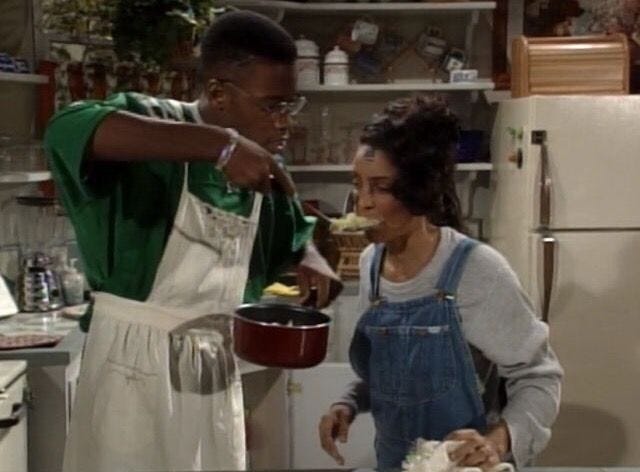 This may contain: a man and woman in the kitchen preparing food