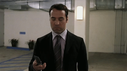 This may contain: a man in a suit and tie looking at his cell phone