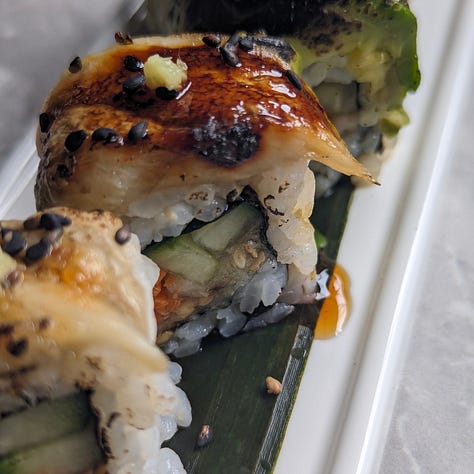 Three types of plant-based uramaki sushi rolls, each topped with colorful ingredients. The rolls have rice on the outside and are sliced into bite-sized pieces.