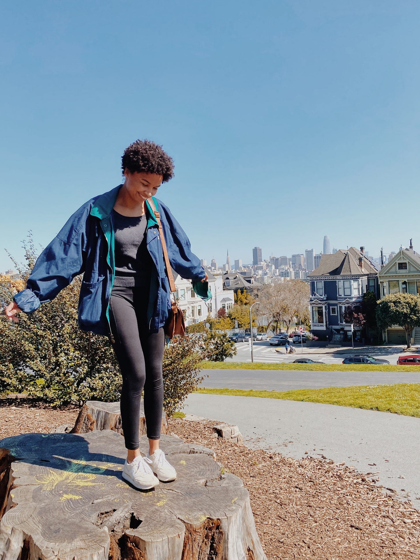 Eden standing on a rock in front of the skyline of San Francisco on a clear blue day