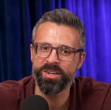 A person with a beard and glasses speaking into a microphone

AI-generated content may be incorrect.