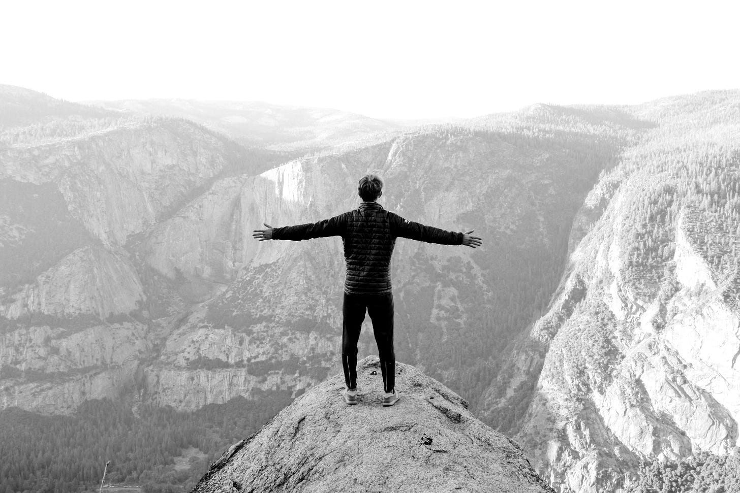 man opening his arms wide open on snow covered cliff with view of mountains during daytime man opening his arms wide open on snow covered cliff with view of mountains during daytime