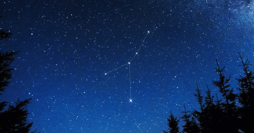 Photo of a dark night sky speckled with stars. A line tracing down to two separate lines indicates the constellation Cancer.