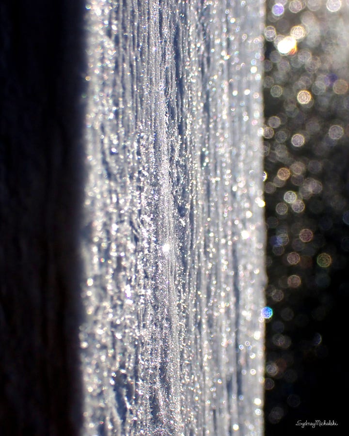 A series of four naturally abstract photographs features vertical stripes of glittering white and golden tones fading into backgrounds of midnight blue and black.