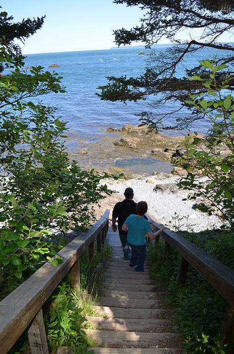 Lighthouse in Maine with rocky beaches and children playing.