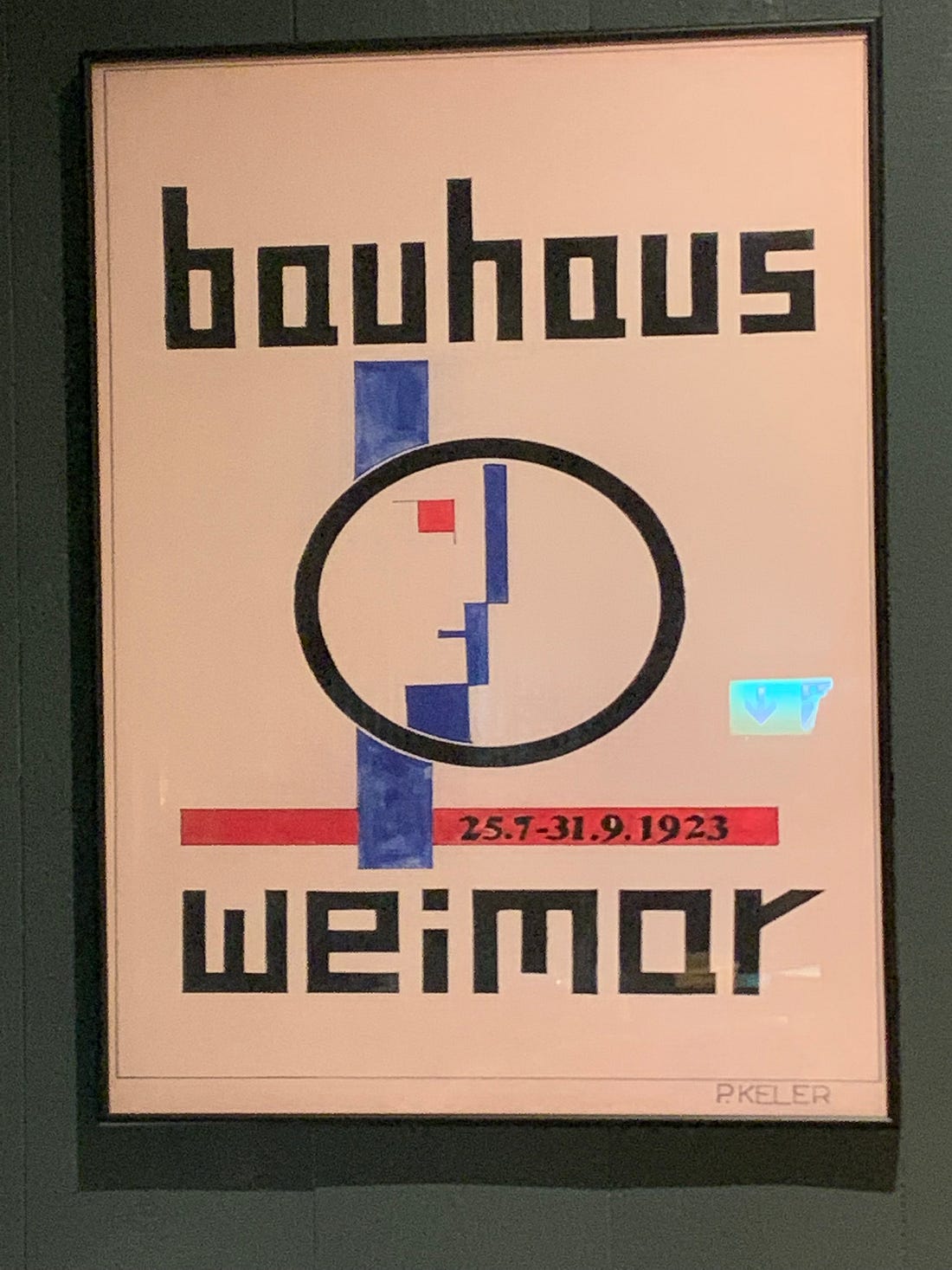 A reproduction of the Bauhaus exhibition poster framed on a dark wall