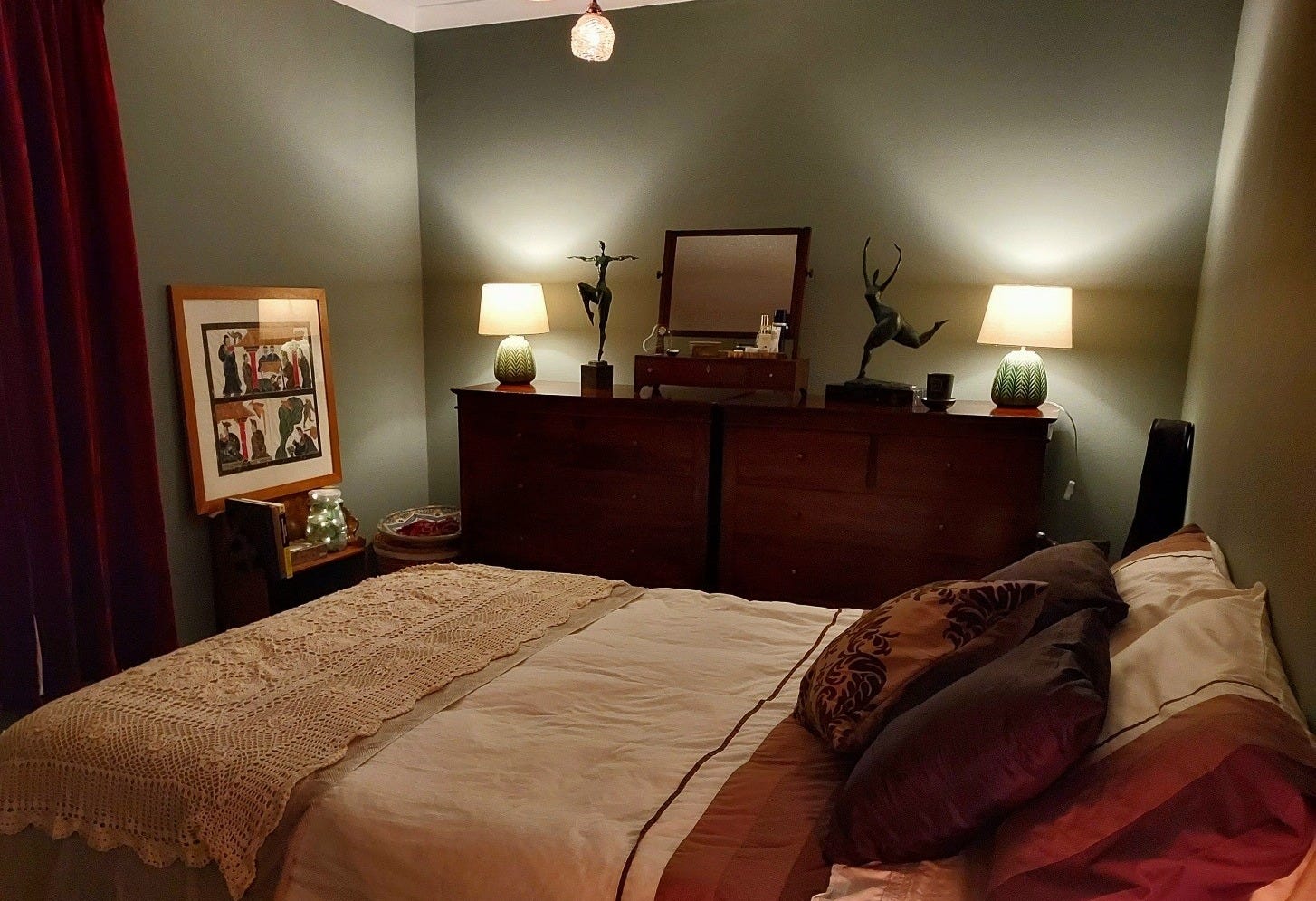 A bedroom, softly lit, with deep, soothing green walls