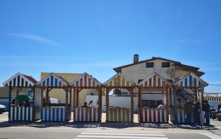 Small, wood stalls with striped paint, selling fish. 