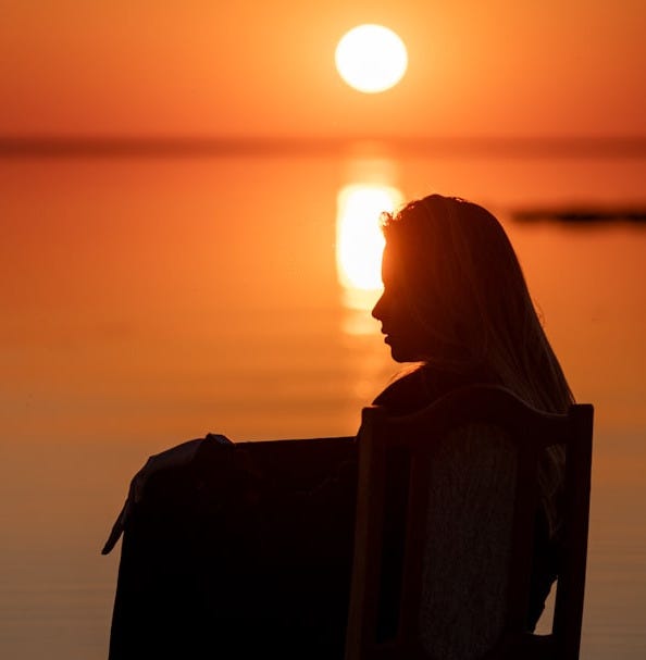 Woman watching a beautiful sunset over the water