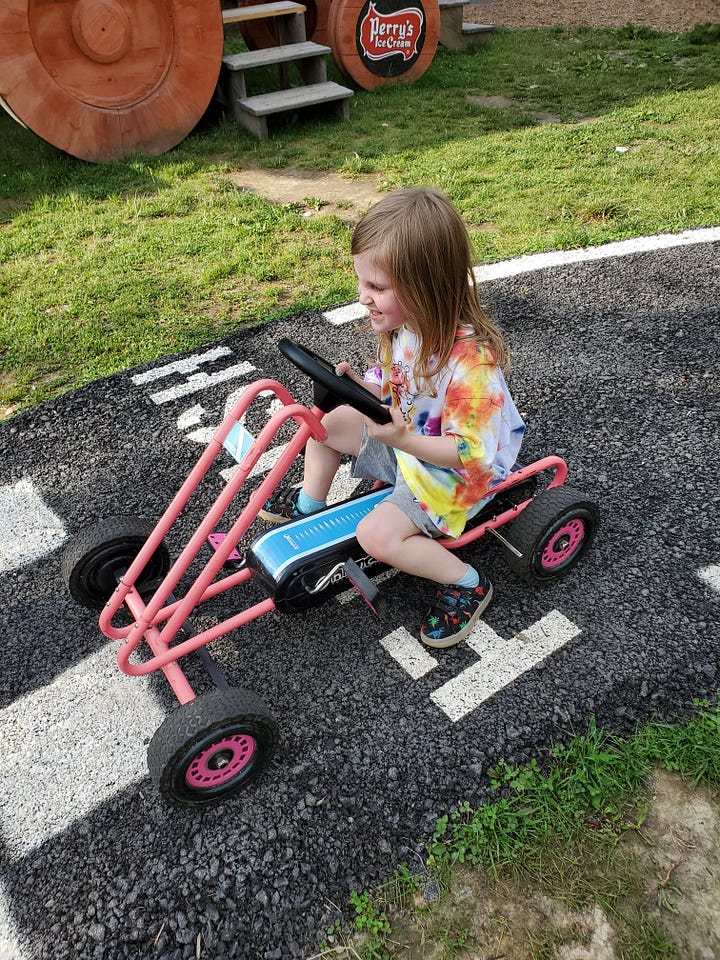 Each photo features a very determined child on a small pedal-driven go-kart type thing on a little paved track.