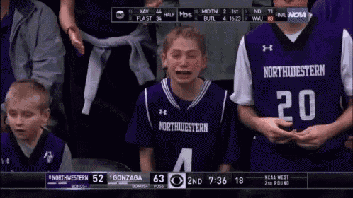 a boy wearing a northwestern jersey is crying during a basketball game