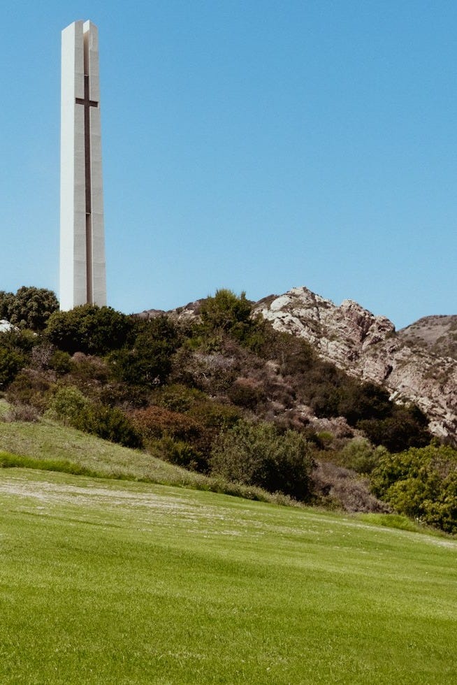 a tall monument on top of a lush green hillside