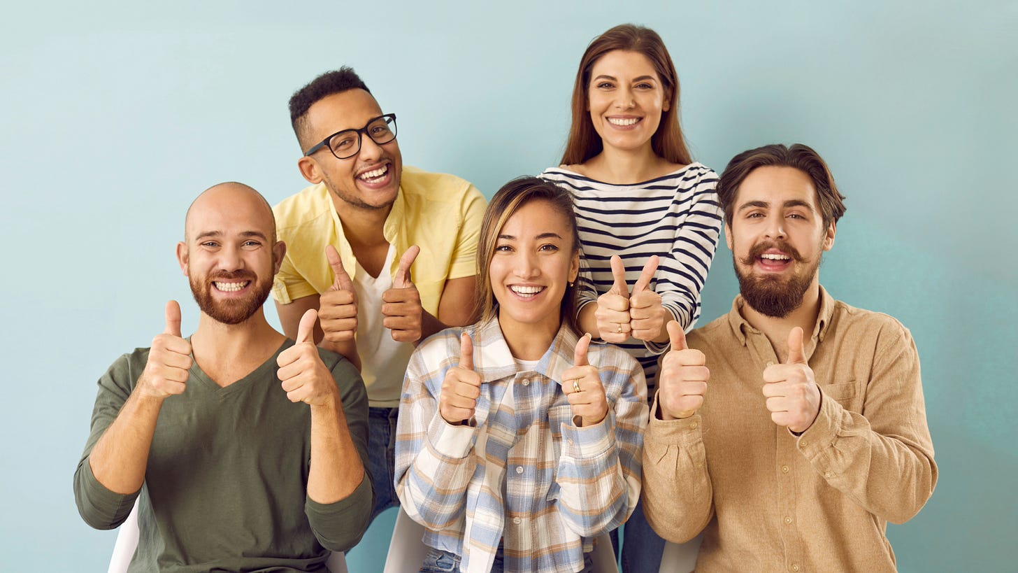 A group of men and women smile and give the thumbs up. A group of men and women smile and give the thumbs up.