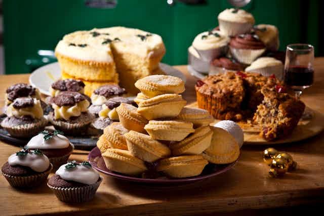 Frosted cupcakes, muffins and sliced cakes are laid out on a table Frosted cupcakes, muffins and sliced cakes are laid out on a table
