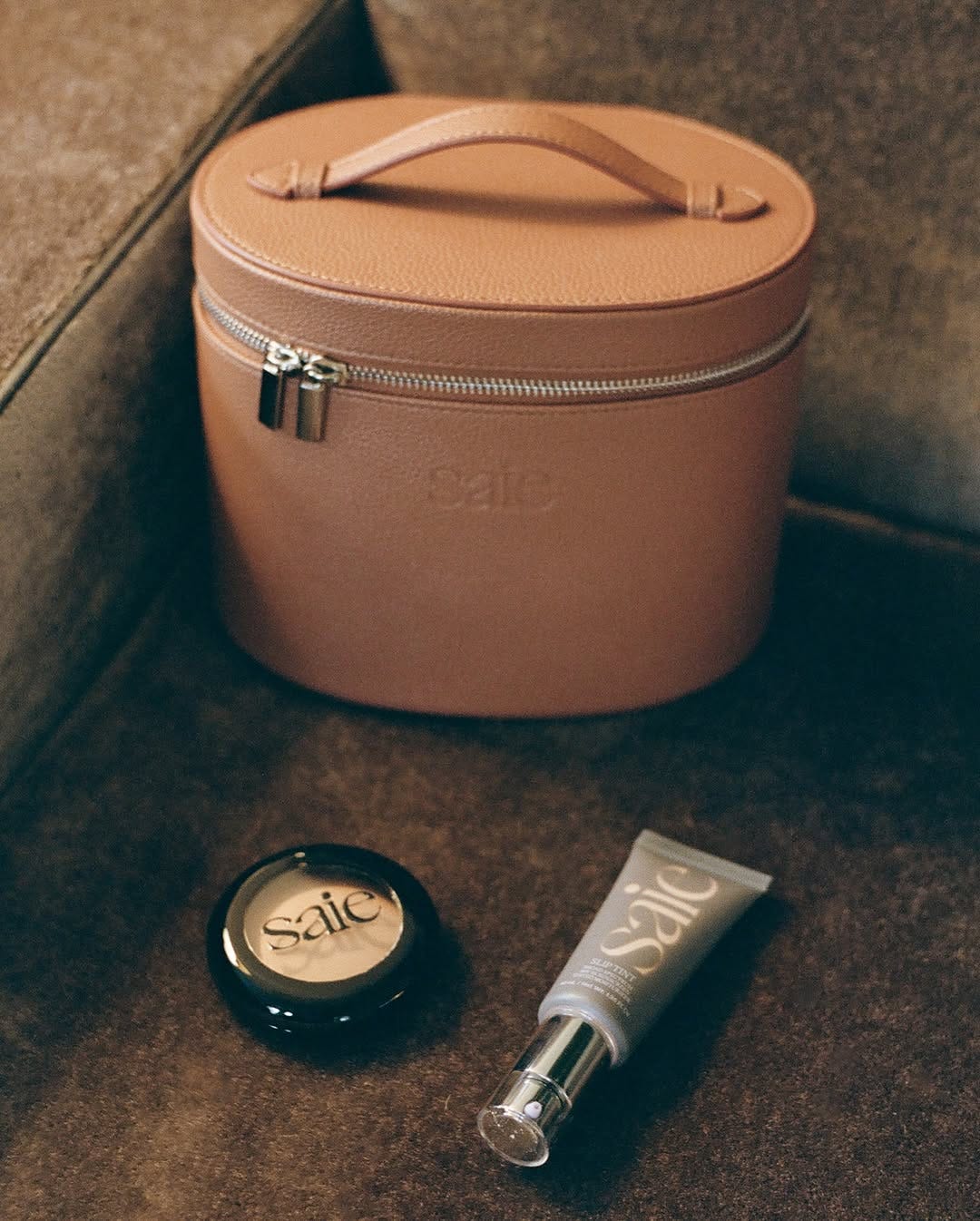 A brown leather vanity case alongside Saie makeup.