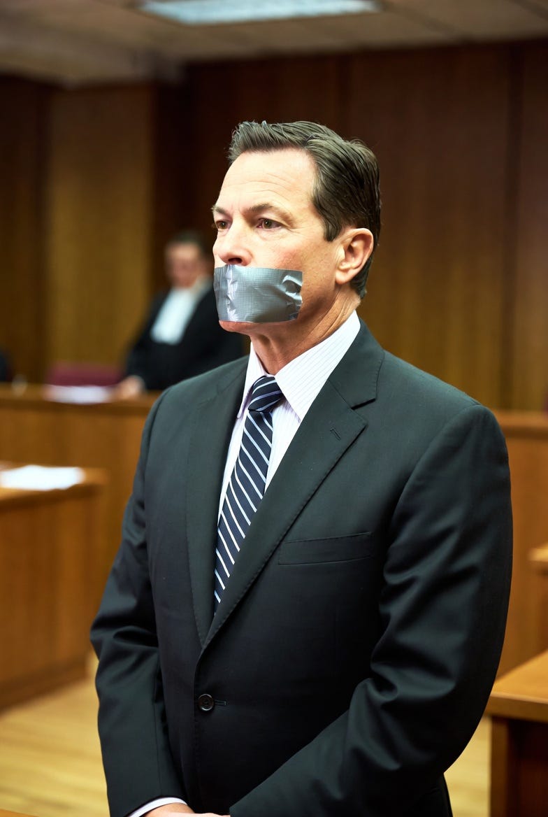 a lawyer standing in a courtroom with duct tape firmly placed over his mouth